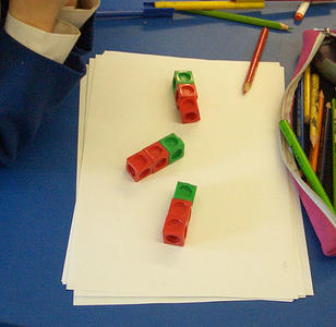 Three trains of coloured cubes, each train with two red cubes and one green, not aligned.